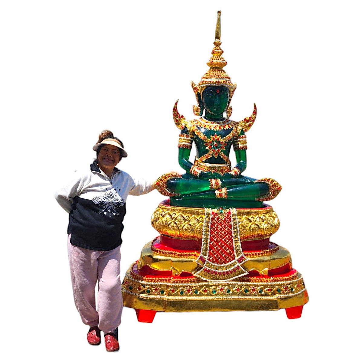 Emerald Buddha replica in green with gold attire on a tiered red and gold base, with a person for scale
