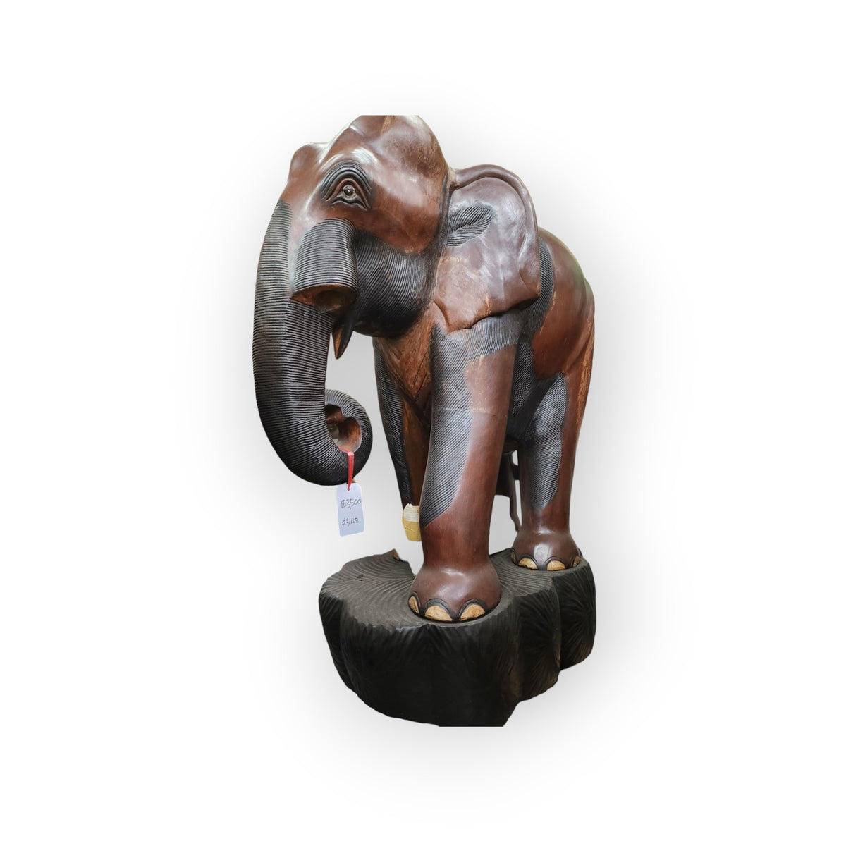 Front three-quarter view of the carved wood elephant with curled trunk