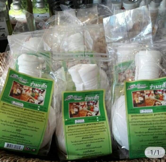 Packs of Thai herbal compress balls in clear bags with green Thai-language labels