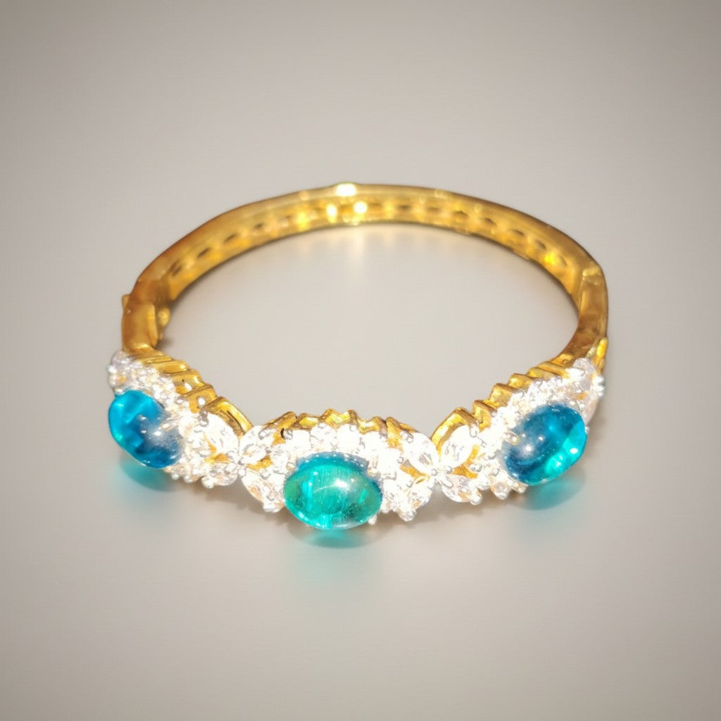 Dipped gold bangle with turquoise cabochon stones and clear stone accents, angled view