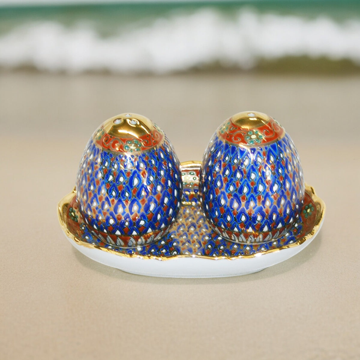 Benjarong salt and pepper shakers on a matching tray, blue and gold pattern, shown outdoors