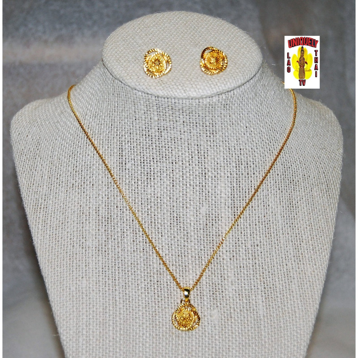 Gold-plated necklace and earring set on a display bust