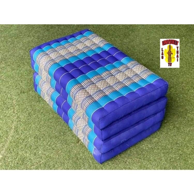 Folded blue kapok Thai futon on grass