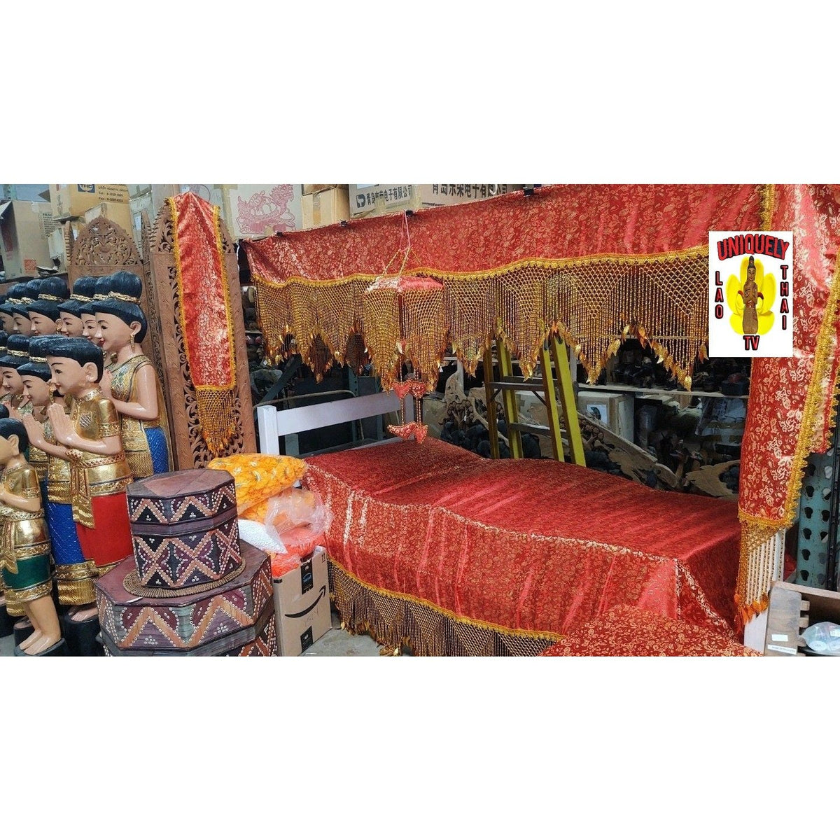 Red brocade funeral canopy with gold bead fringe, displayed over a bed